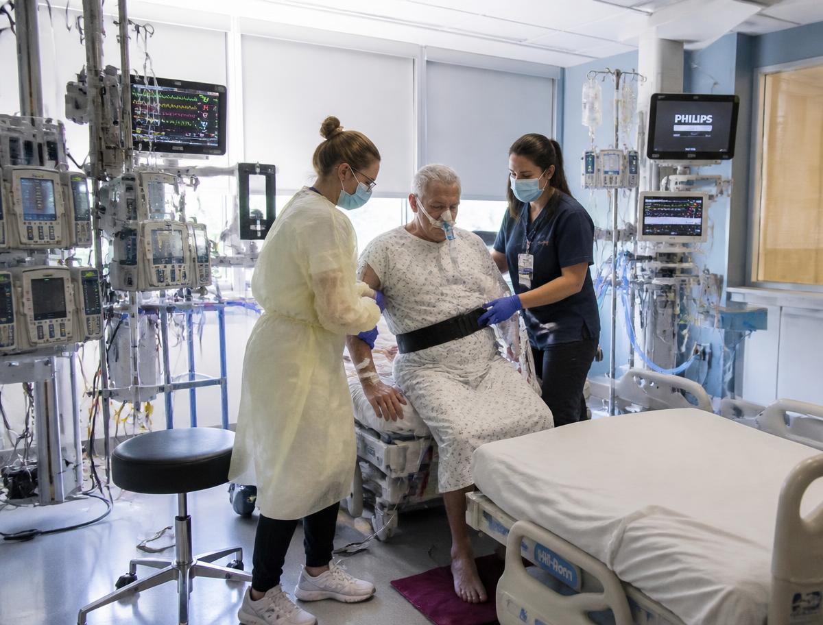 Therapist mobilising a critically ill patient at the bedside in an intensive care unit
